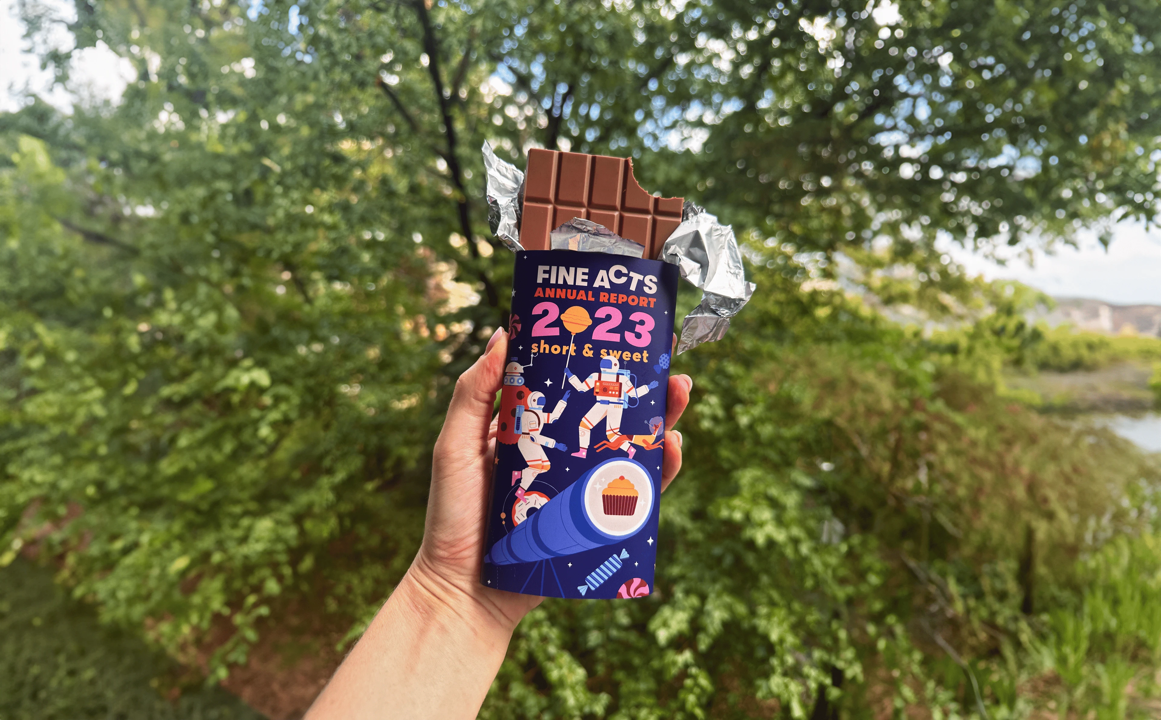 Fine Acts chocolate bar held outdoors beside a river