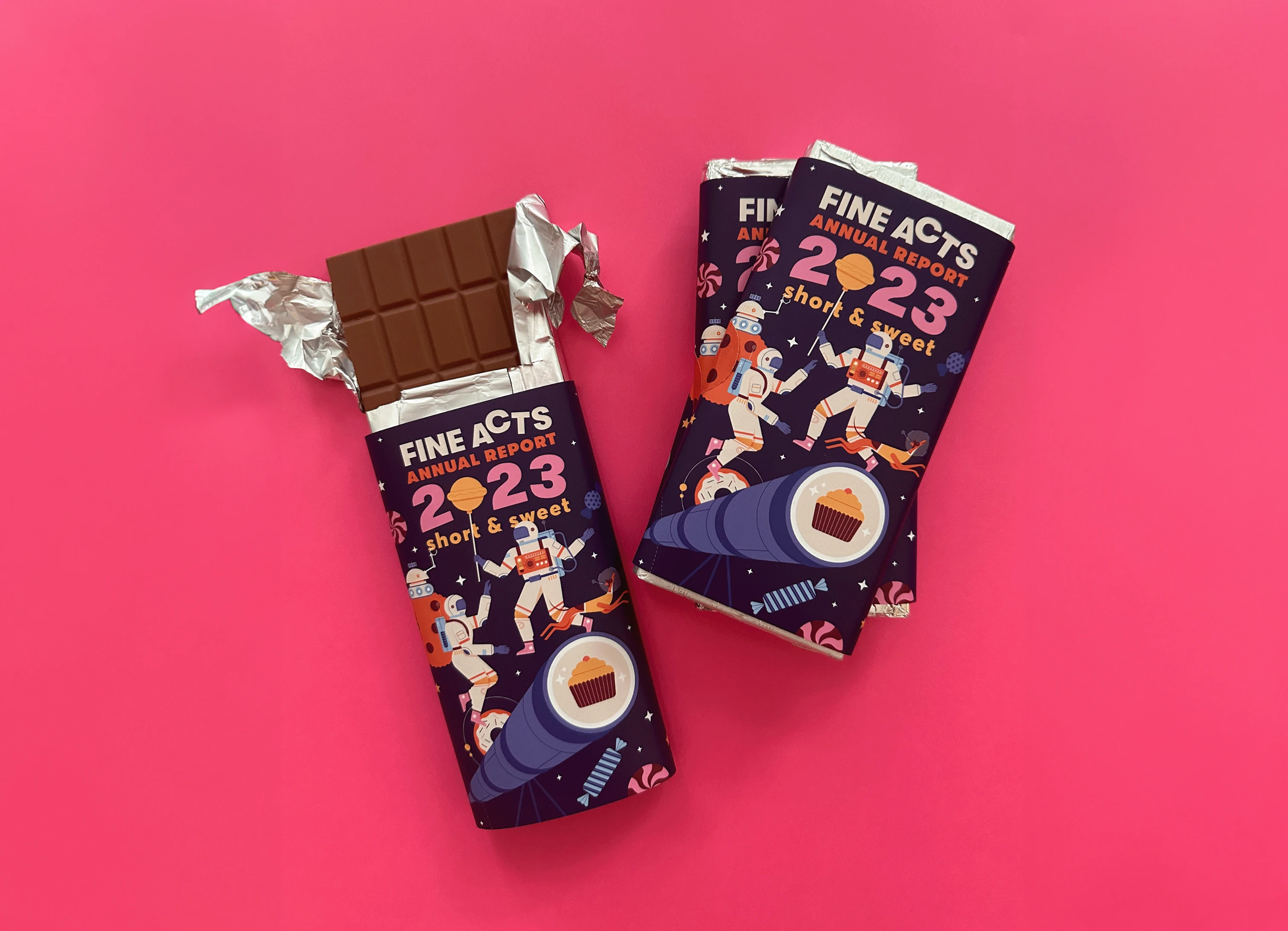 Unwrapped and wrapped Fine Acts chocolate bars on a pink background